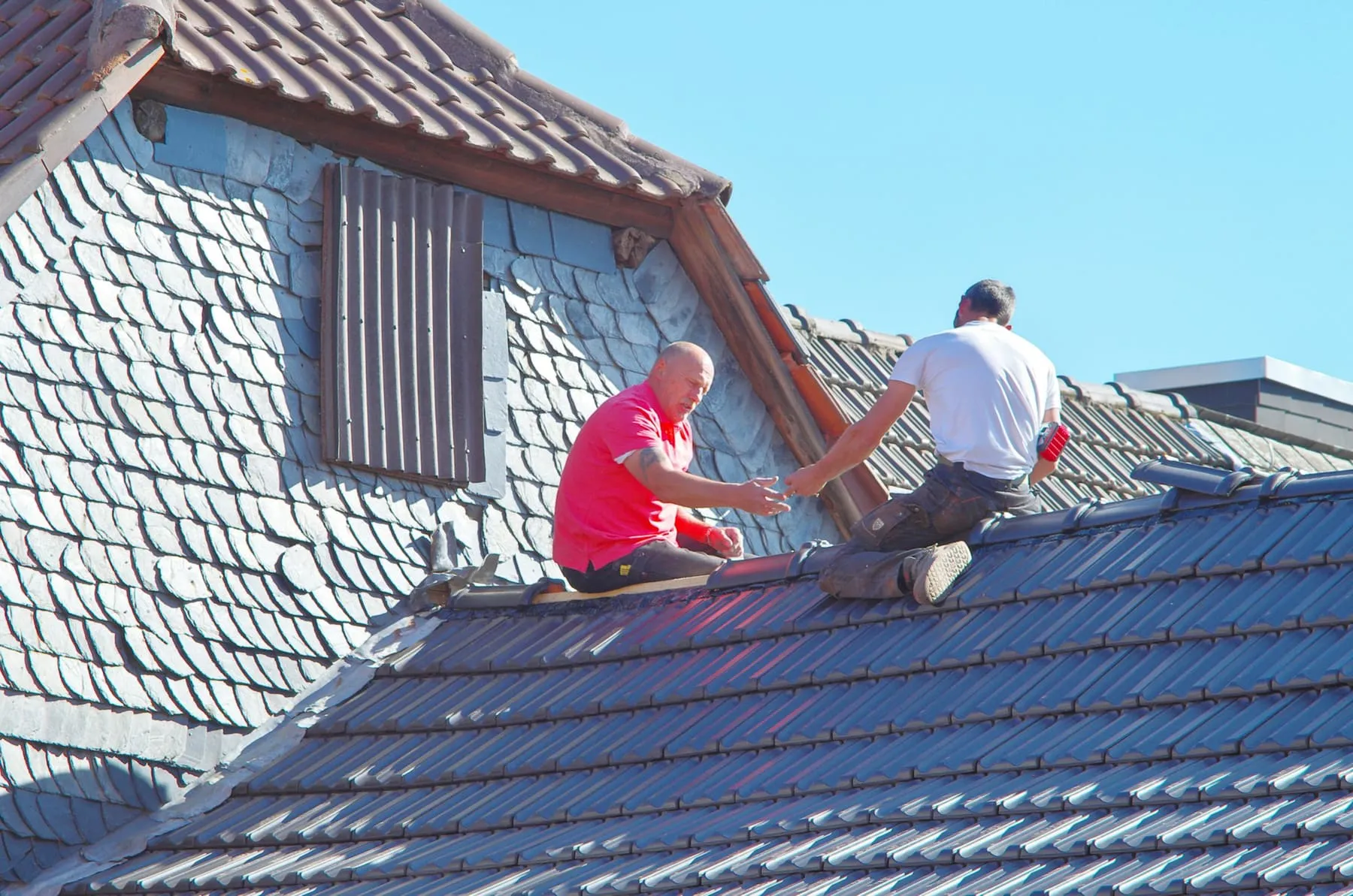 Deux couvreurs travaillant sur un toit en ardoise