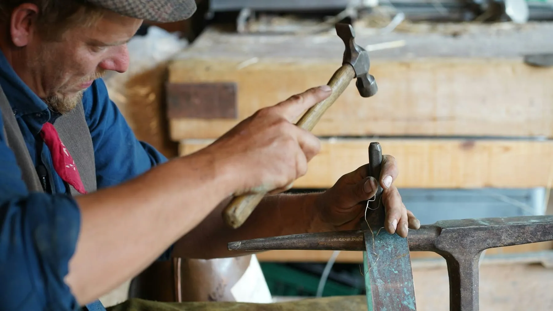 Compagnon martelant une bande de métal sur l’enclume de l’atelier