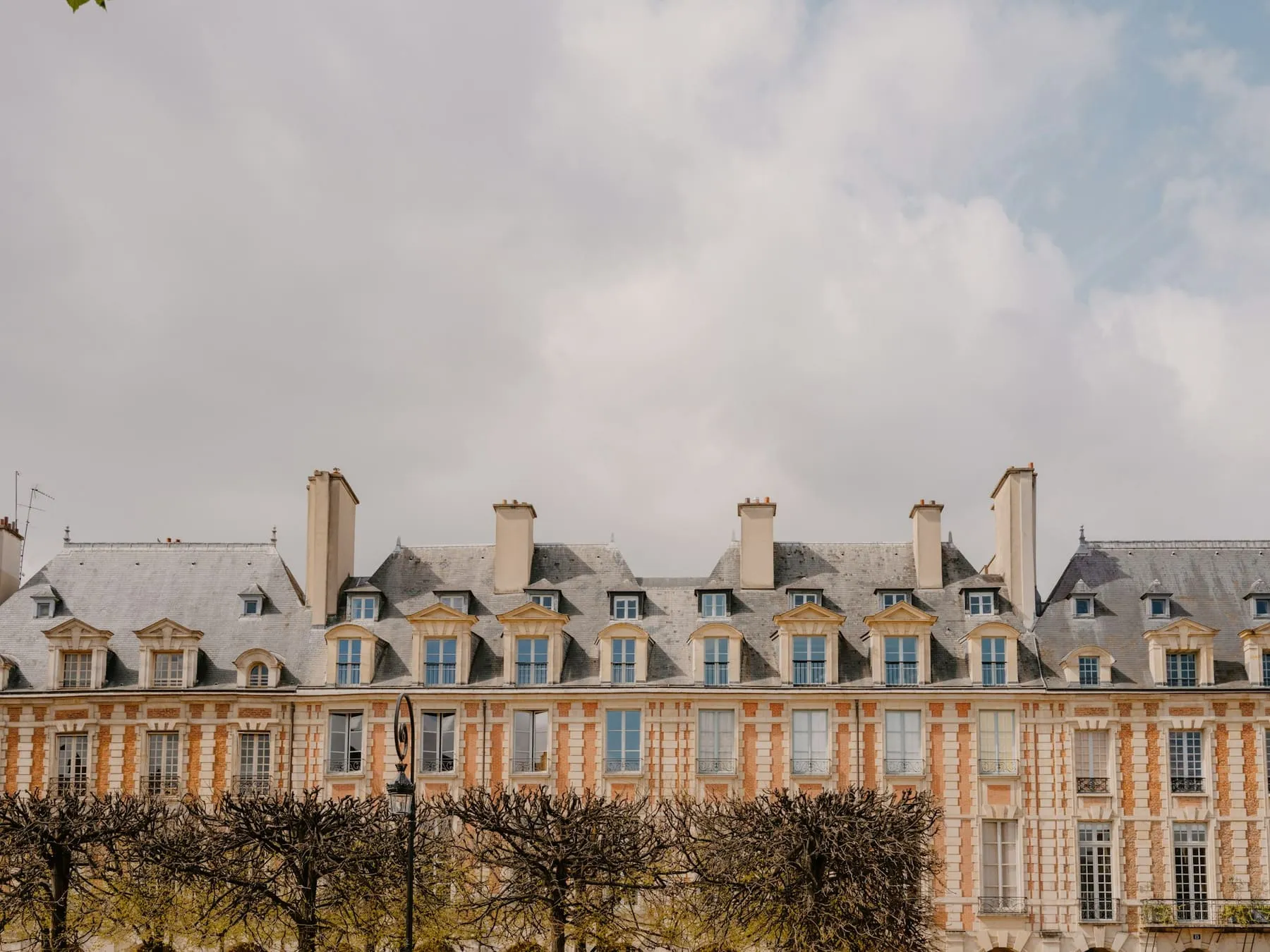 Façades en brique et toits d’ardoise autour d’une place du Marais