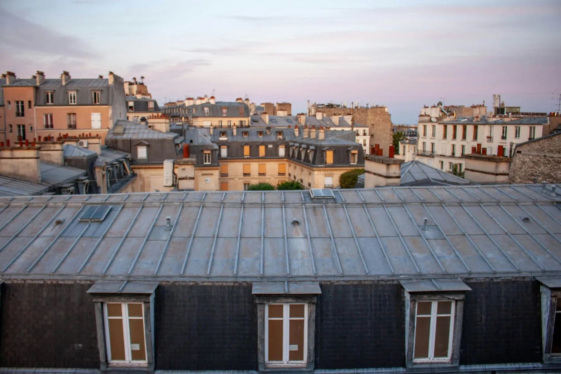 Toits en zinc et lucarnes d’immeubles parisiens au coucher du soleil